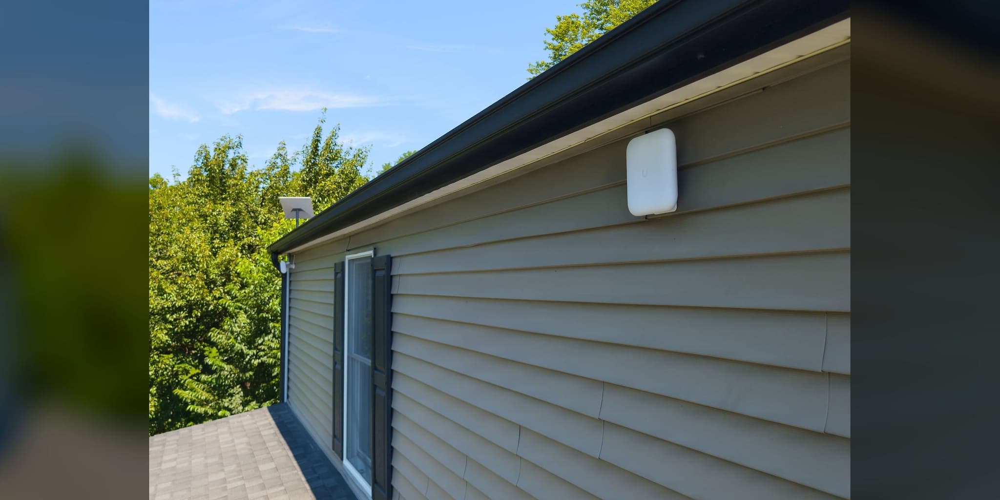 Outdoor-rated UniFi access point wall-mounted on a building exterior (representative photo)