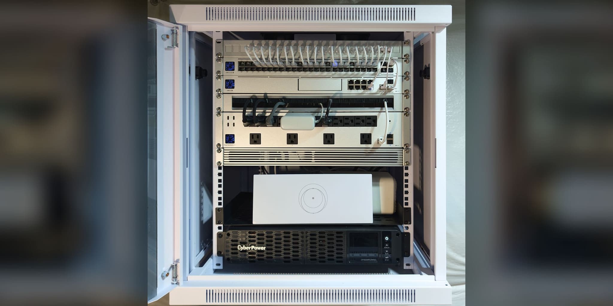 Commissioned 12U basement wall cabinet in Partlow, VA — labeled patch panel, USW Pro Max 48 PoE switch, UDM SE gateway, metered power distribution, Starlink router, and pure sine-wave UPS