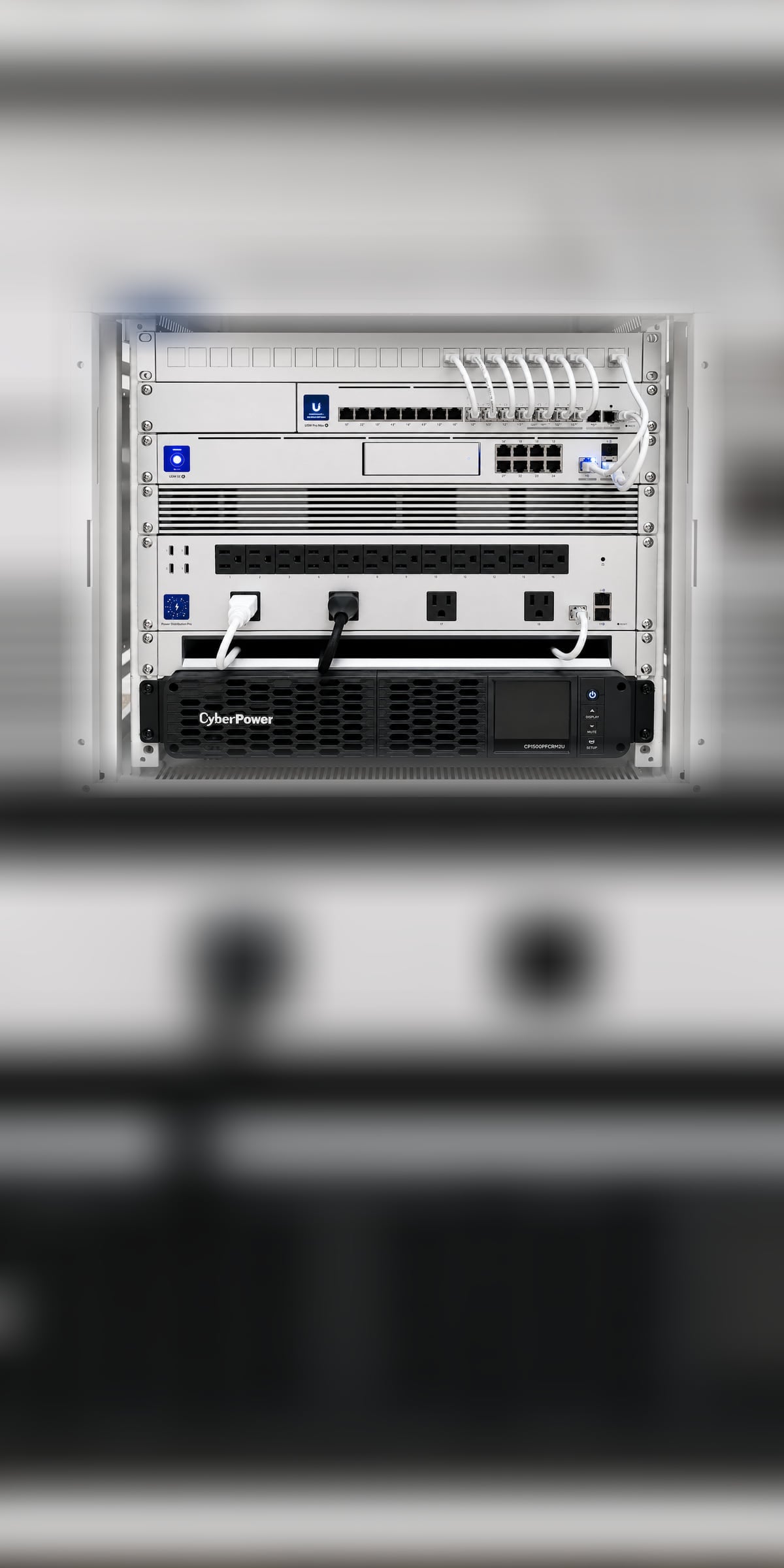 Commissioned executive network core — patch panel, UniFi USW Pro Max switch, UDM SE gateway, rack power distribution, and rack-mount UPS in a white enclosure