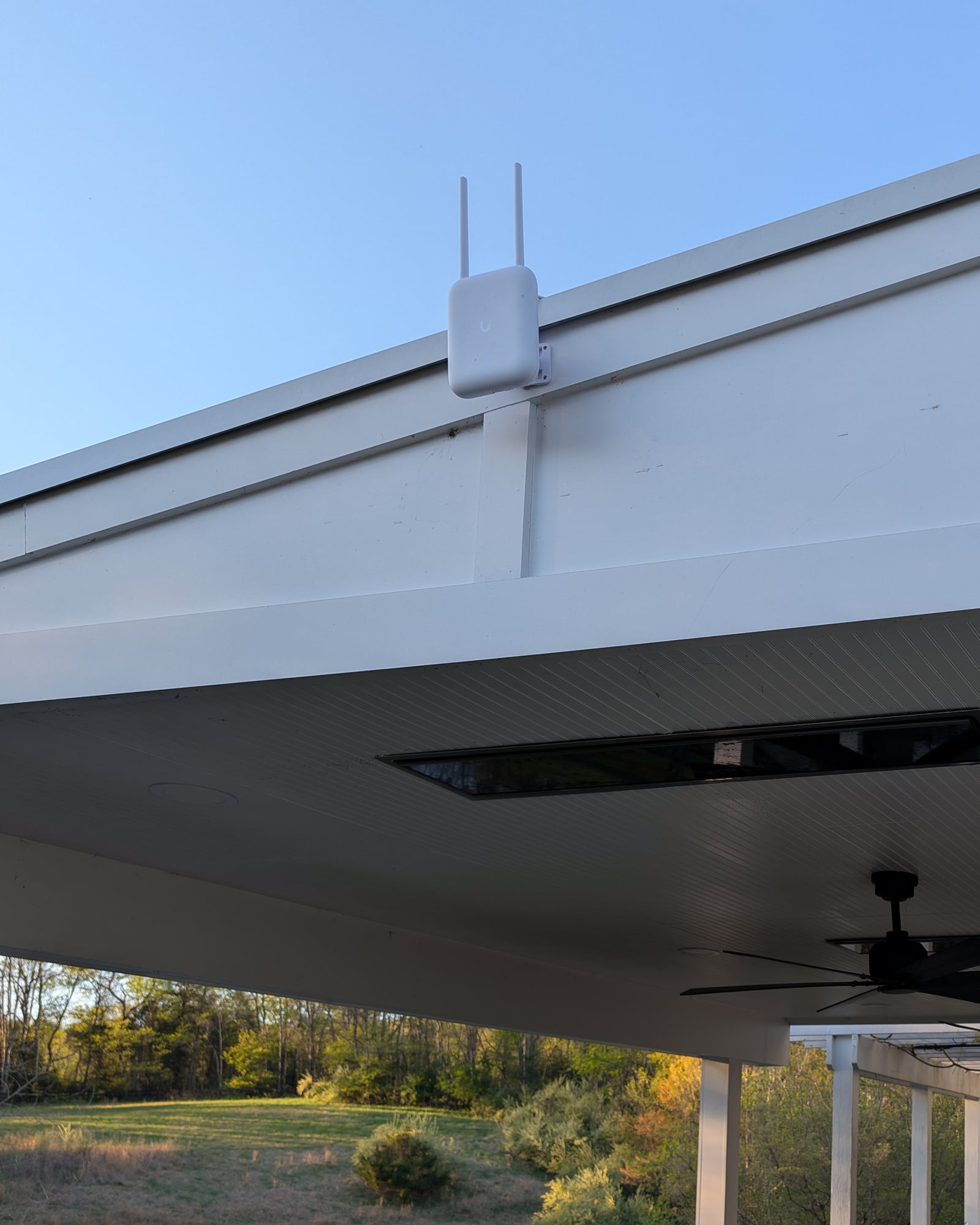 Outdoor UniFi access point mounted on a white pavilion fascia above the grounds — Castleton, Virginia estate