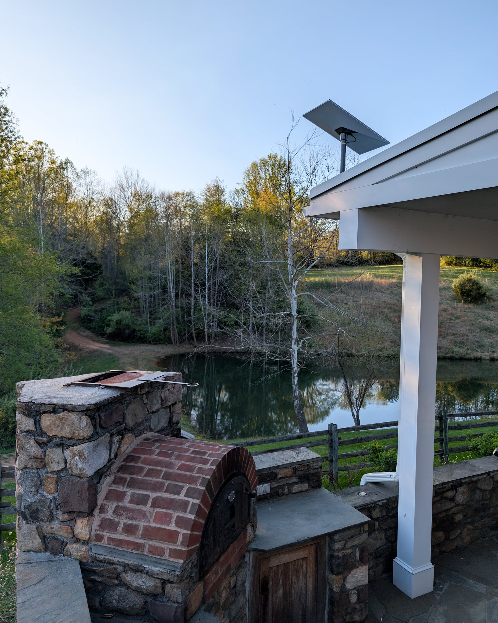 Starlink dish at the pavilion roofline over the estate pond at dusk — Castleton, Virginia estate