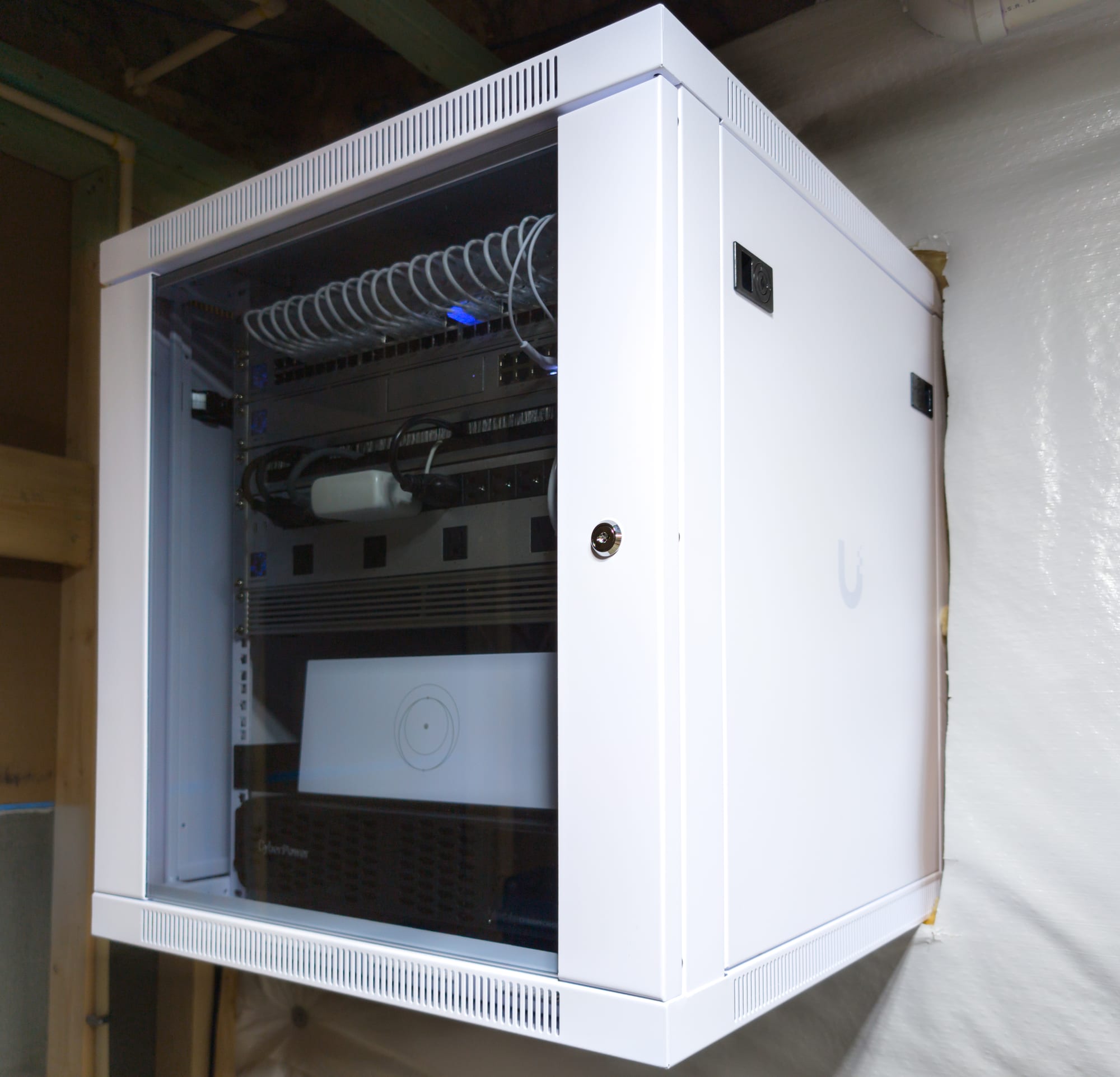 Commissioned white wall-mount network enclosure with locking glass door, closed after handoff