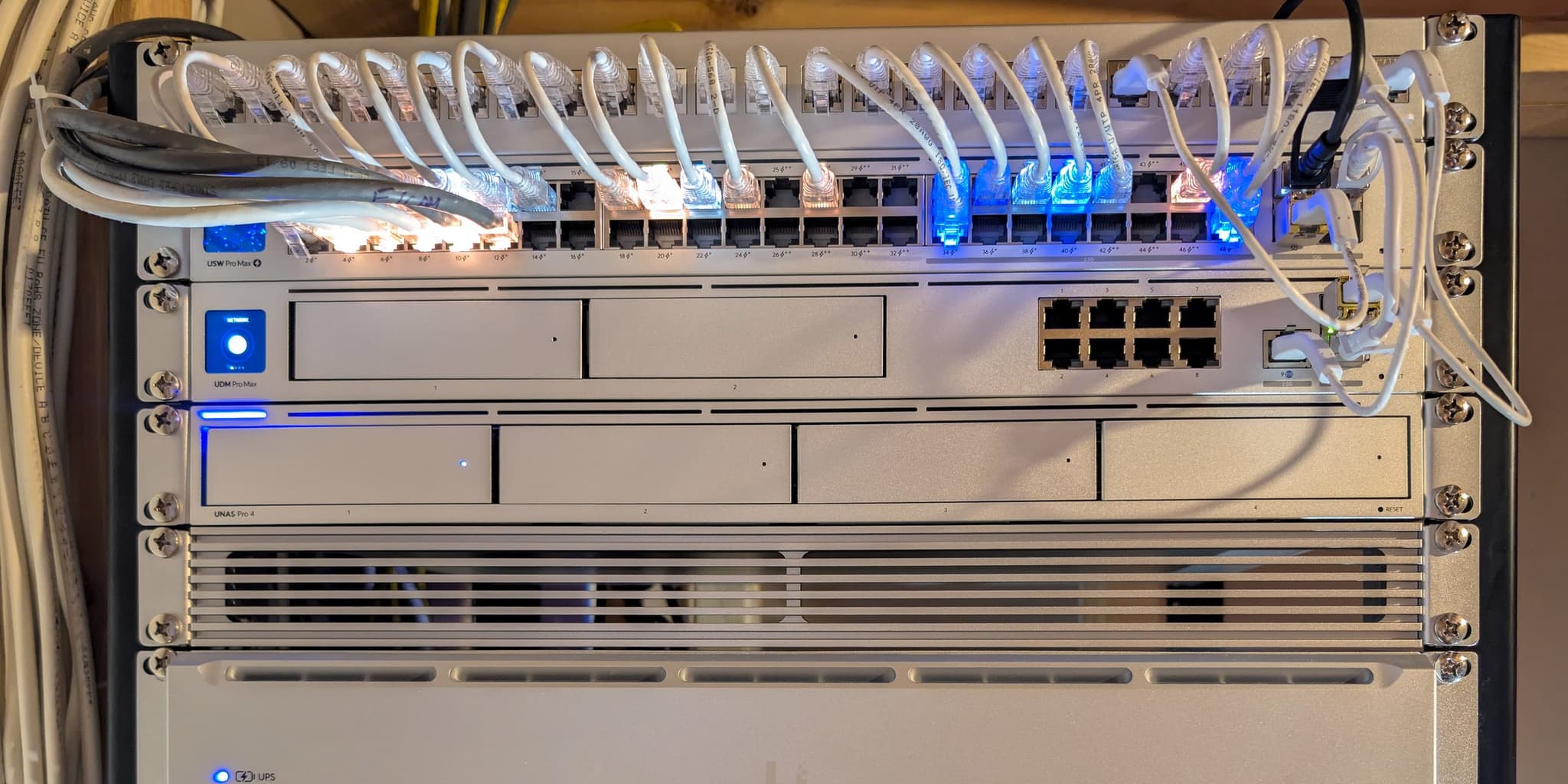 Wall-mounted network rack in Alexandria, VA — patch panel with dressed patch leads, UniFi PoE switch, gateway, storage, and UPS