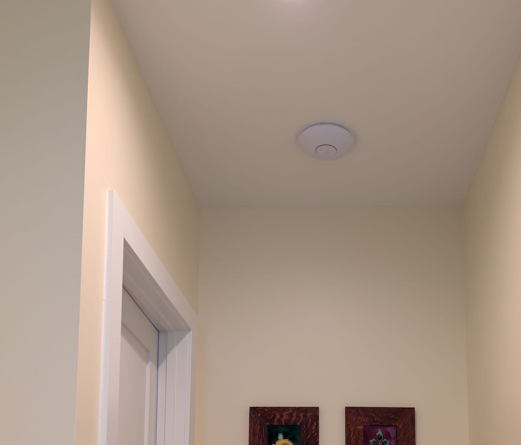 Ceiling-mounted UniFi access point in a building corridor (representative photo)