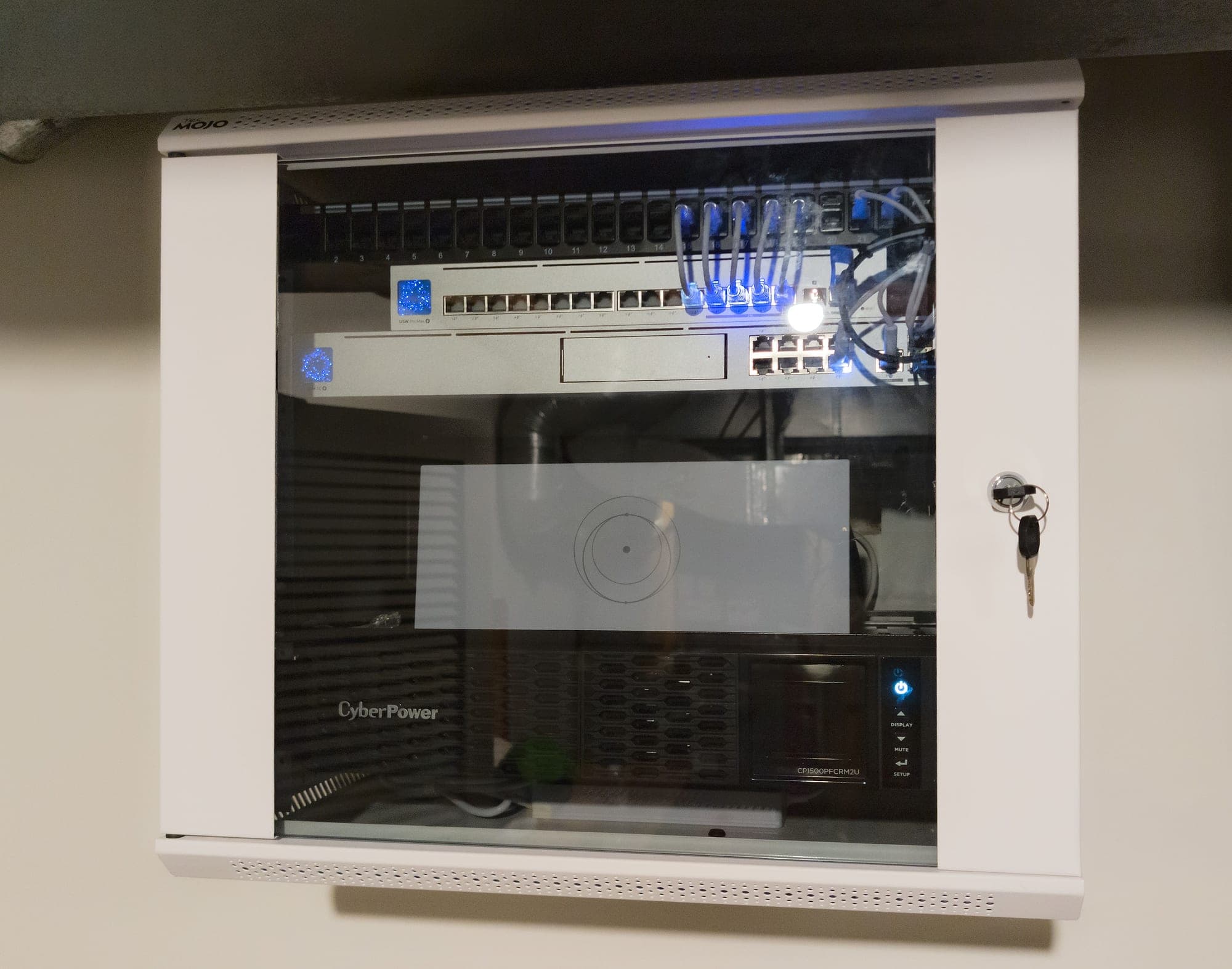 Network cabinet detail — patch panel above PoE switching, rack UPS at the base (representative photo)