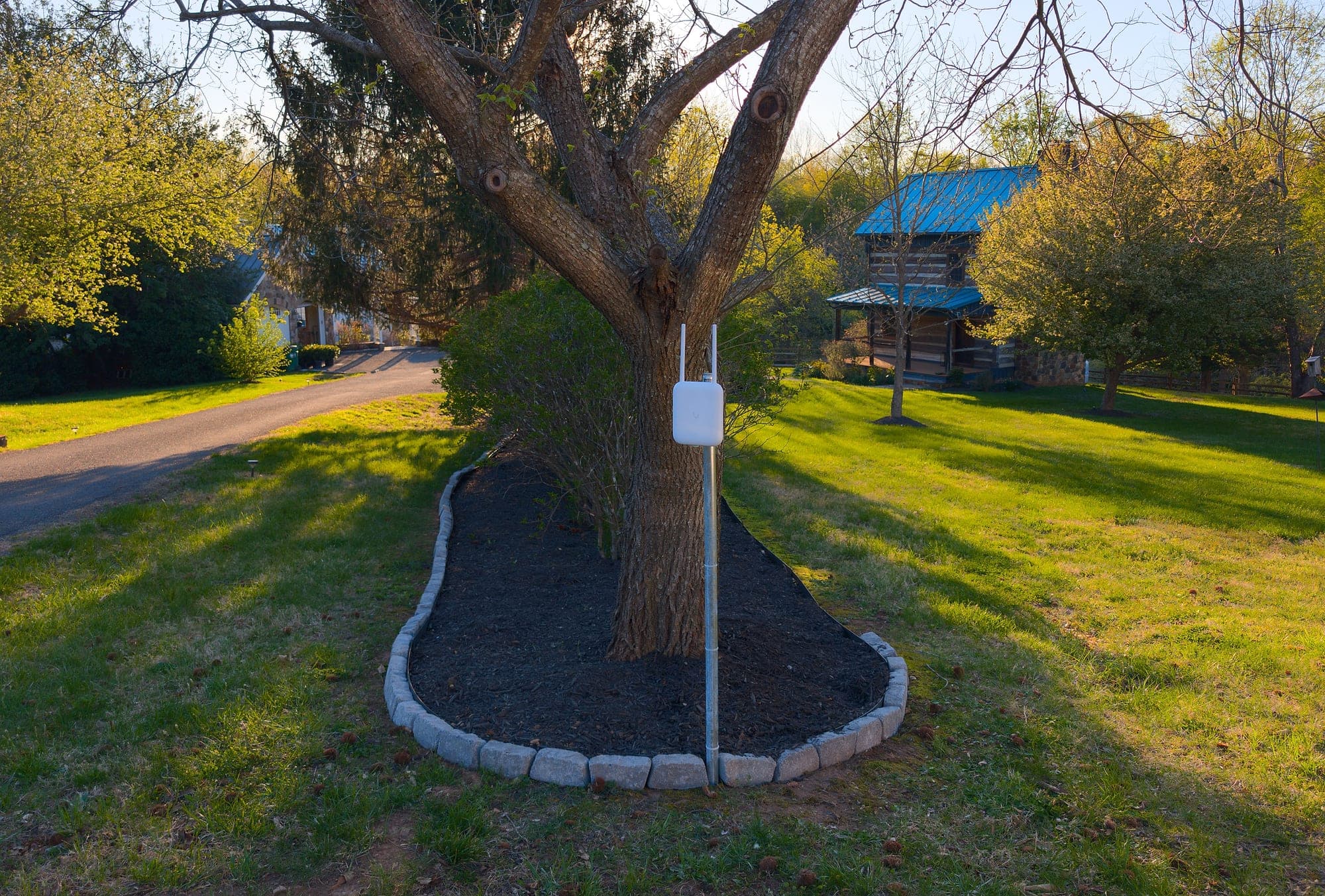 Post-mounted U7 Pro Outdoor at the driveway midpoint between the main house and the log cabin