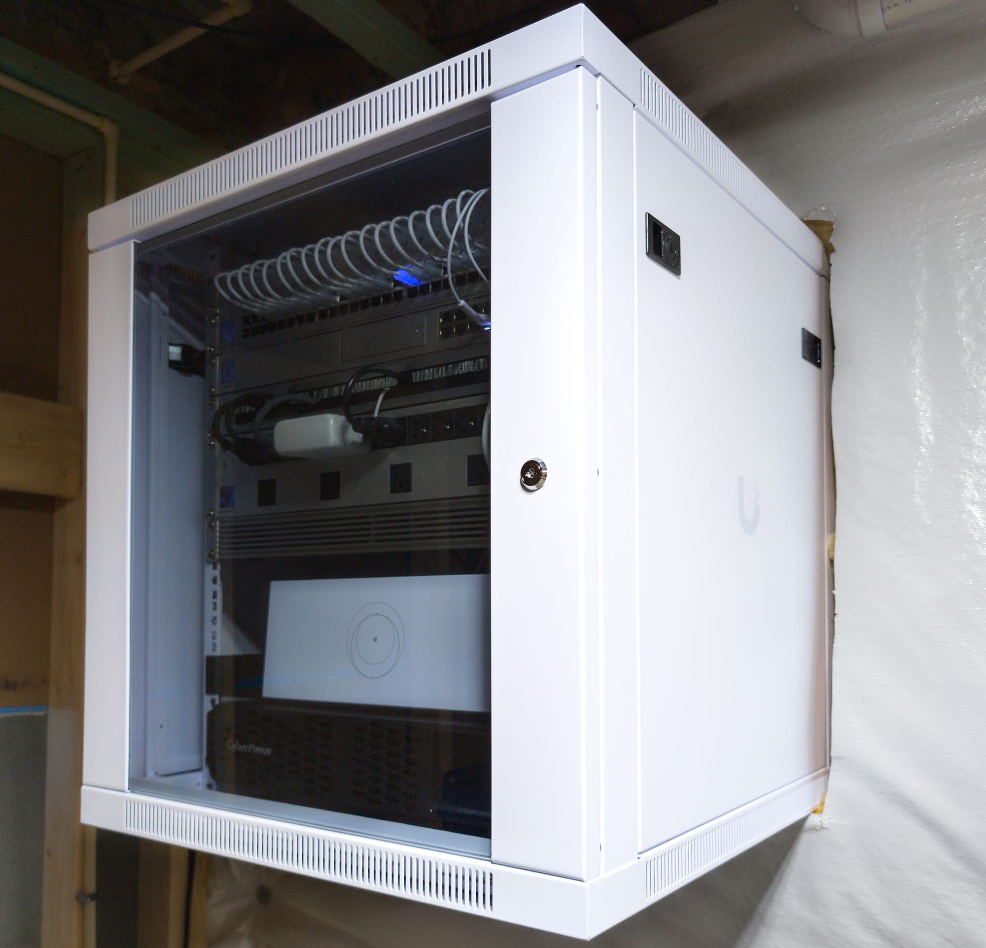 12U wall-mount cabinet closed, locking glass door, mounted to the basement wall