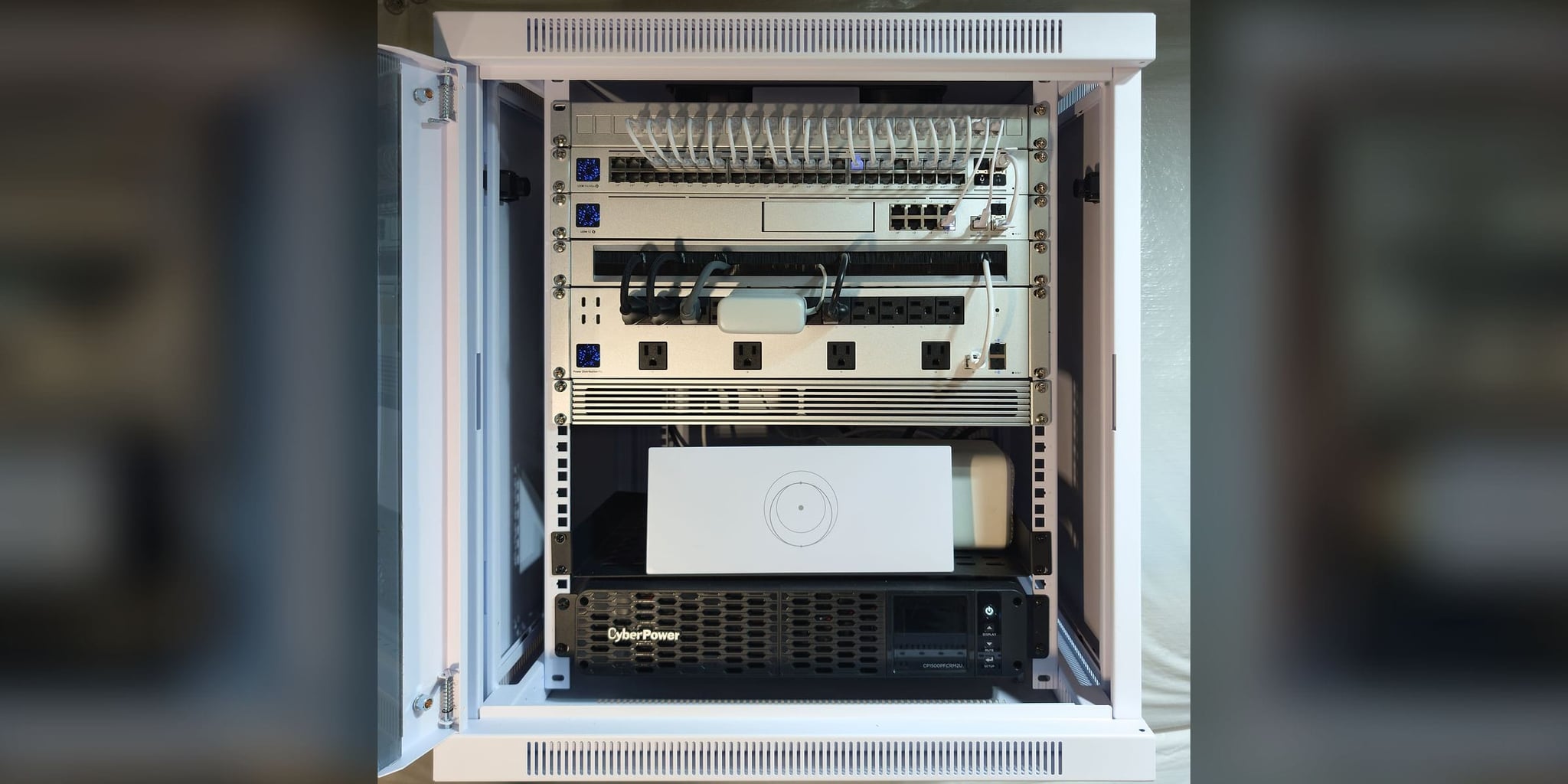 Commissioned 12U basement wall cabinet in Partlow, VA — labeled patch panel, USW Pro Max 48 PoE switch, UDM SE gateway, metered power distribution, Starlink router, and pure sine-wave UPS