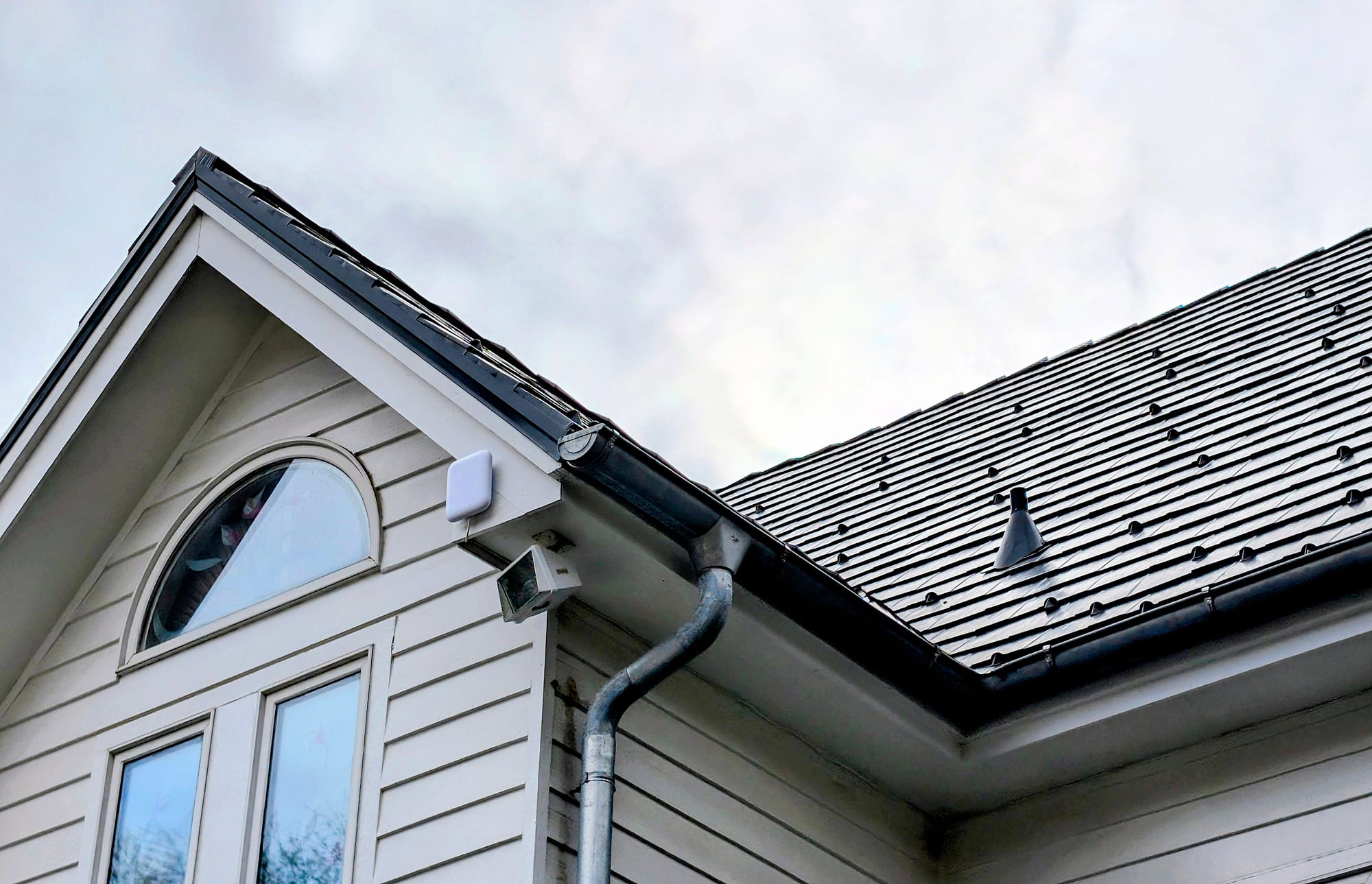 Gable end and roofline of the same Potomac house, with a small white unit and a floodlight under the eave
